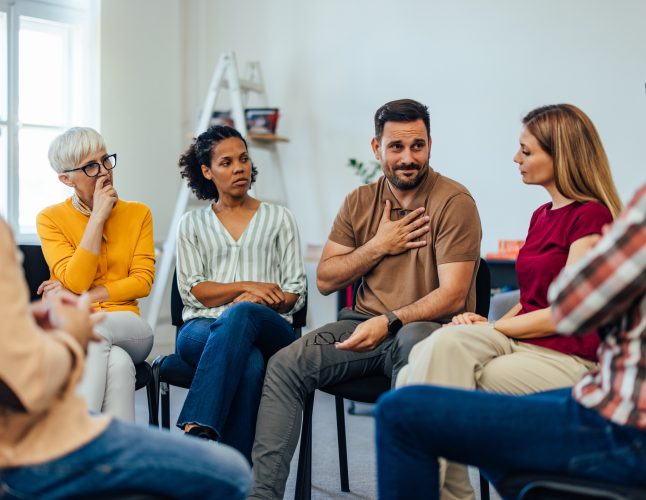 People sitting in a circle, having a group mental health therapy.