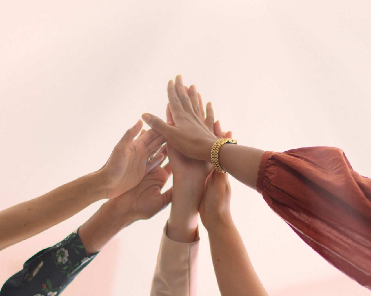 A diverse group of women, celebrate teamwork with high-fives. Joyful teamwork women high-fives. Group of businesswomen achievement high-fives. Cheerful diverse women team high-fives for achievement